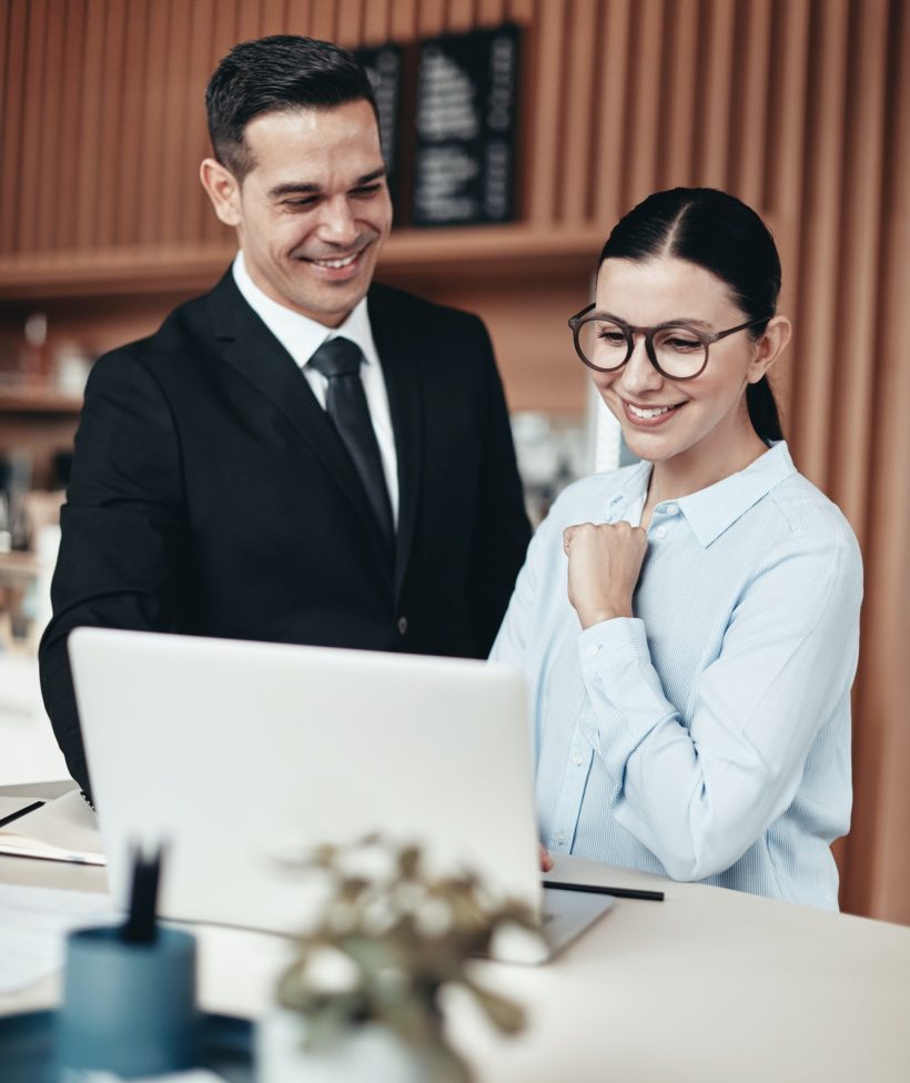 two-smiling-businesspeople-using-a-laptop-together-in-an-office.jpg